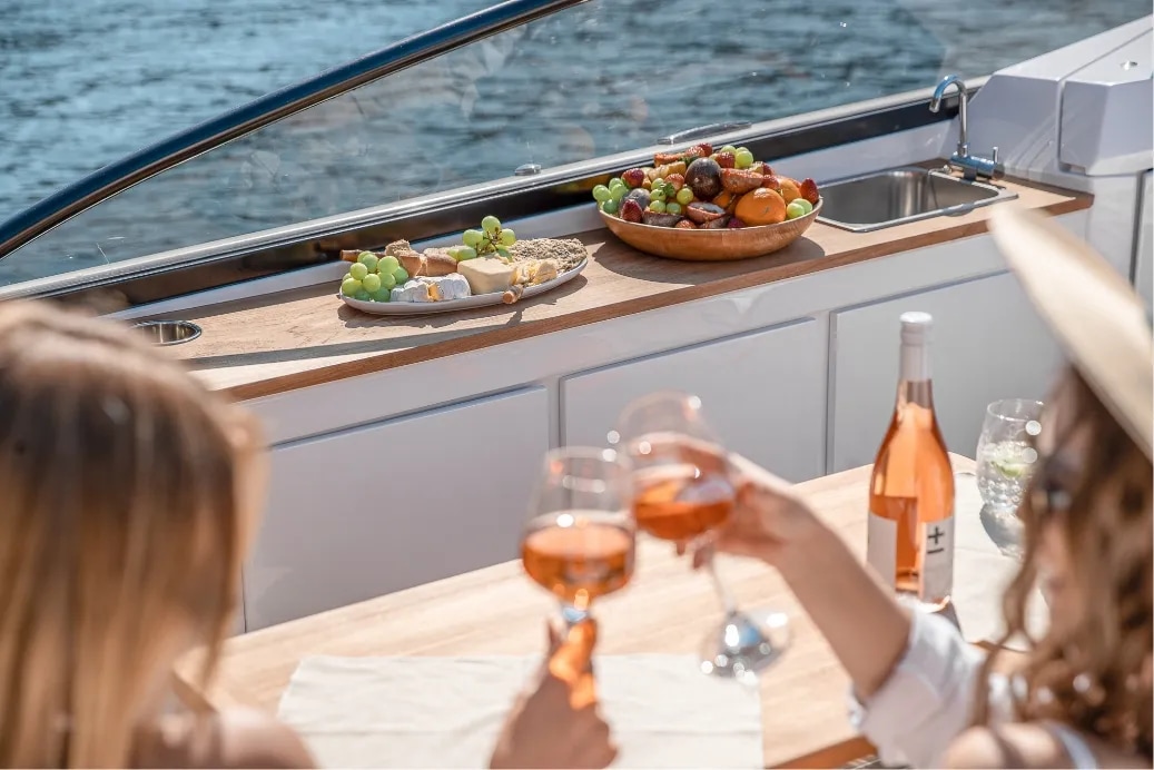 Two women sharing a glass of wine beside the portside galley, from RAND’s Leisure 28 gallery